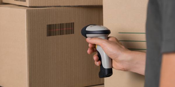 Scanning barcode on box Courier scanning cardboard box with barcode scanner in warehouse. Close up of warehouse manager hand scanning boxes with barcode reader. Man reading and scanning labels on boxes.